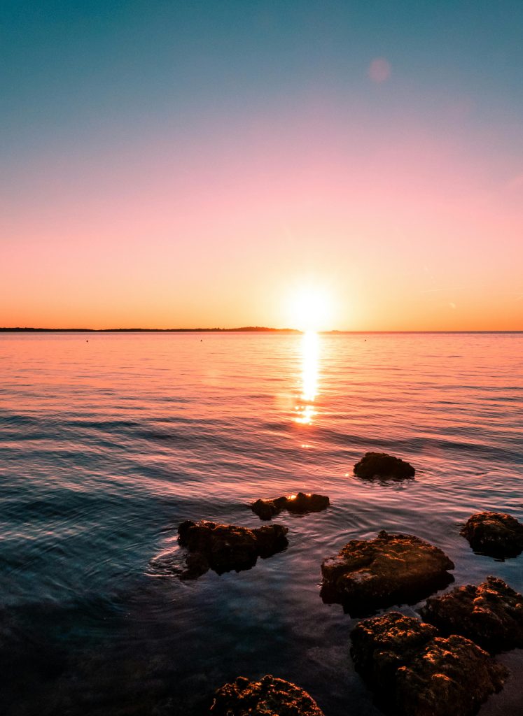 pexels-photo-2261500-2261500 Experience the serene beauty of a sunset in Peroj, overlooking the Adriatic Sea with rocky shores.